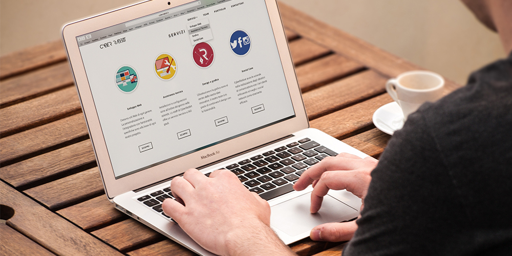 Over the shoulder look at laptop on bistro table, with online newsletter stack open.