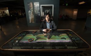 Interactive Visualization Exhibit with person seated behind it, showing moving mountains beneath their hands.