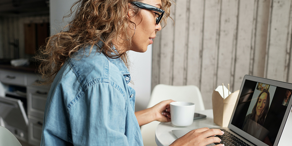 Video call and use of social media as two small business women chat over coffee.