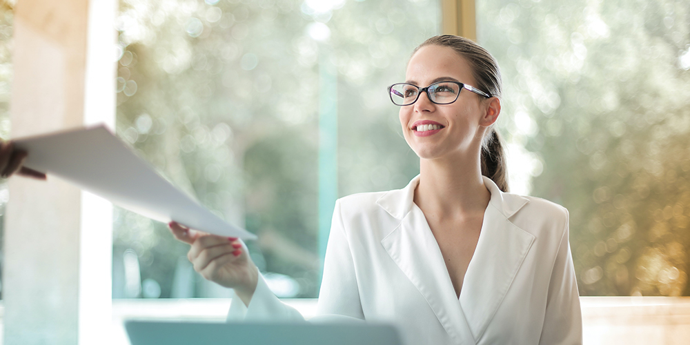 Smiling rockstar employee accepting paper from off screen.