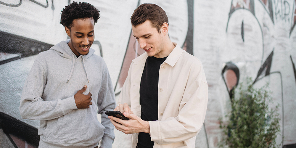 Two men over a phone discussing video marketing with one man approving of content.