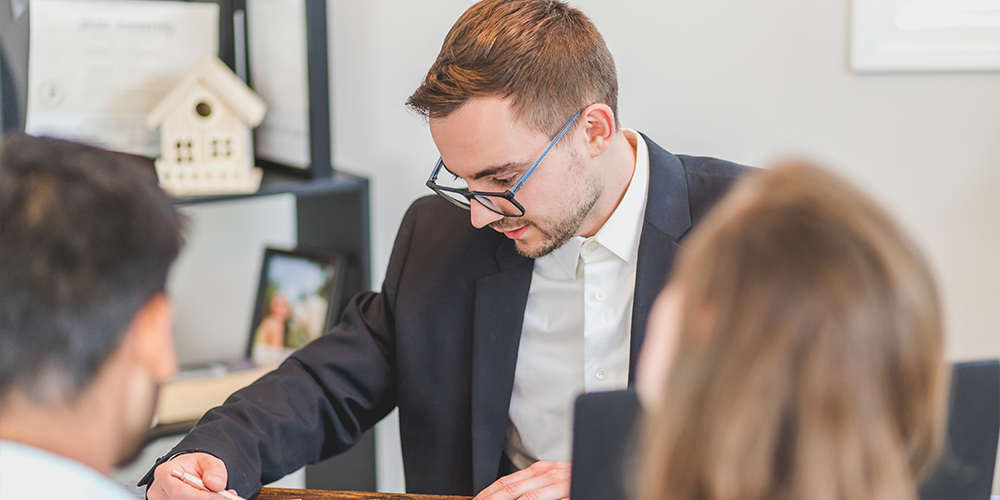 Man reviewing paperwork from Zillow listing with couple looking to buy