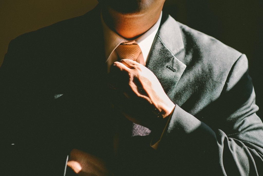 Man in suit fixing tie representing leaders