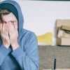 person with face in hands representing young adults living with parents