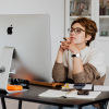 A woman sits in front of a desktop computer with a critical expression as she reads through an email to detect scams