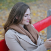 A woman sitting on a red park bench in the fall using her smartphone setting up moving.