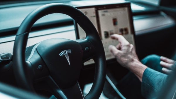 Tesla driver pointing to screen, representing the Toyota CEO saying that the auto industry doubt an EV-only future.
