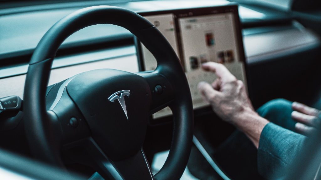 Tesla driver pointing to screen, representing the Toyota CEO saying that the auto industry doubt an EV-only future.