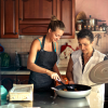 A mother and daughter cook together in a warmly decorated kitchen, part of a trend of multi-generational housing.