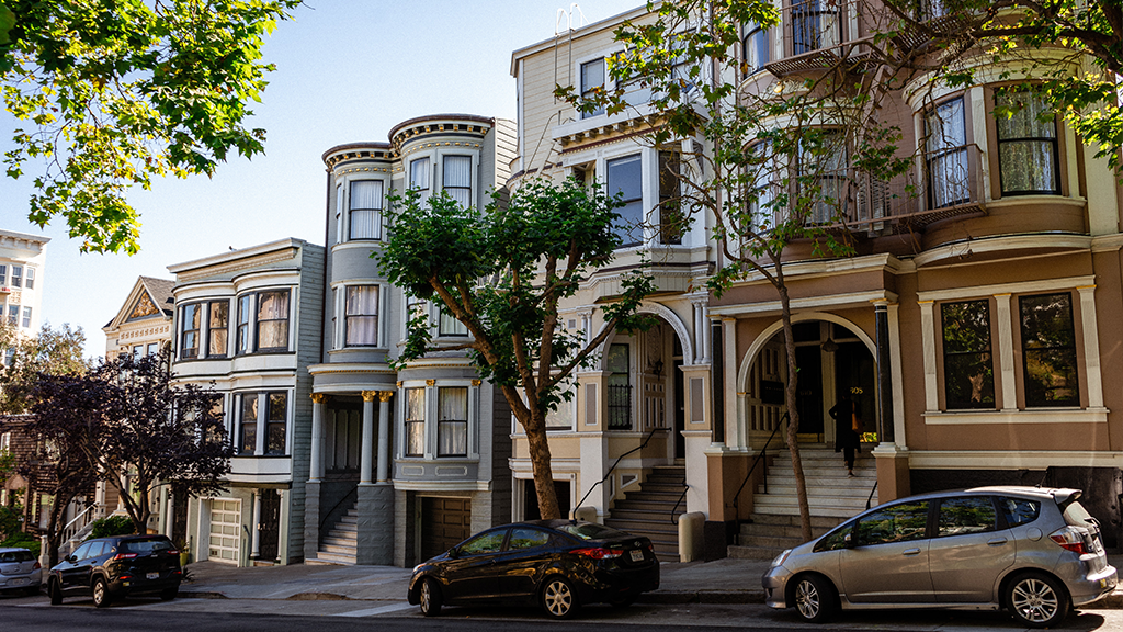 A city street showing close together housing with different home prices