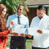 A group of three people stand outside a house with a Realtor in the middle, helping the other two to read the forms of the Nosalek case.