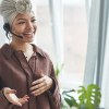 A real estate agent, a woman with her hair wrapped up in a neat cloth on her head, talks on the phone with a hands free setup.