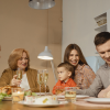 A family with grandparents, parents, and young children, all toasting and talking around a kitchen table, showing a difference in homebuying.