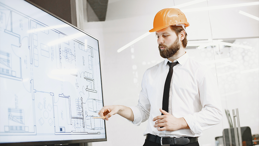 A man in an orange hard hat reviews eminent domain while showing off a schematic for a new building.