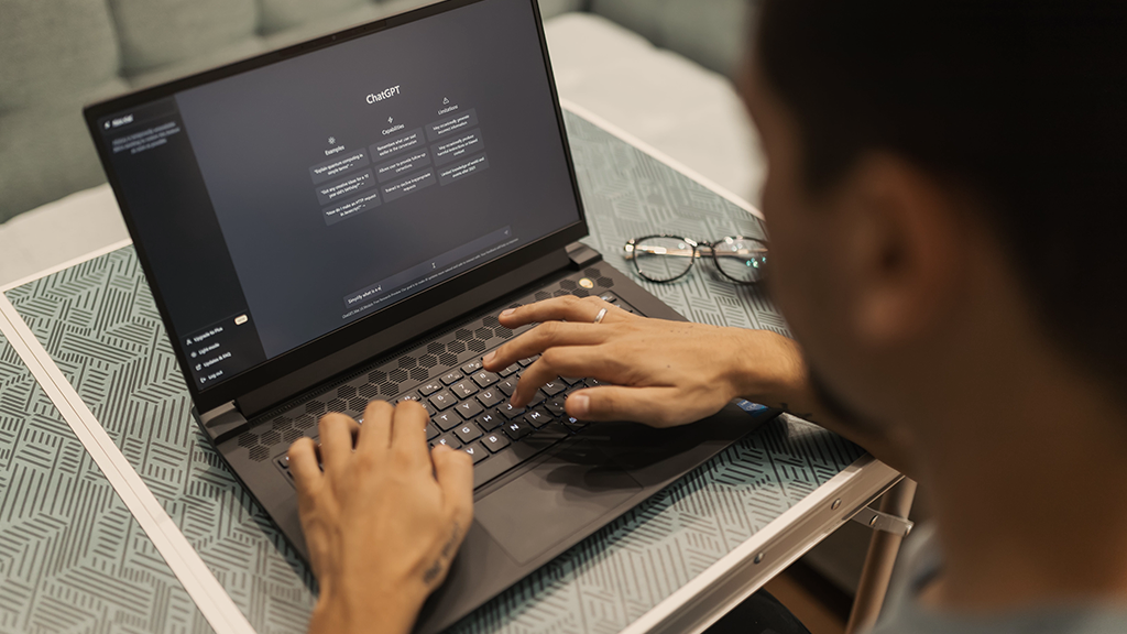 Looking over the shoulder of a man typing on a laptop open to ChatGPT 4 to test its knowledge.