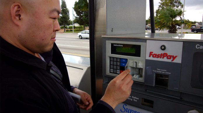 Man inserting card to buy cheap gas at a GasBuddy recommended location.