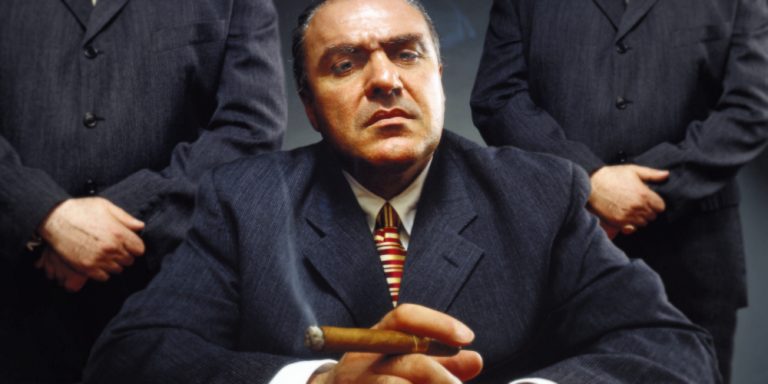 Man will hands folded on table representing the art of persuasion.