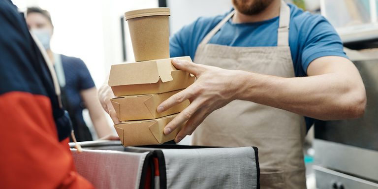 Man carrying small food boxes representing shrinkflation.
