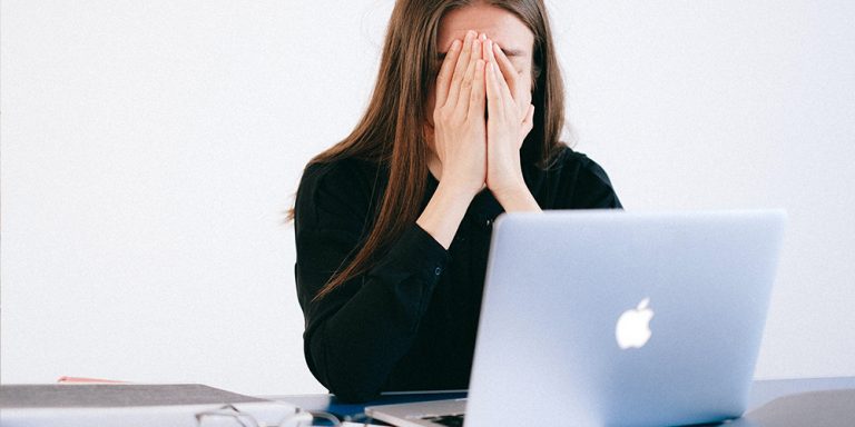 Woman stressed over laptop while working from home.