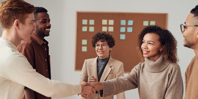 A meeting room with people shaking hands over acquiring a business