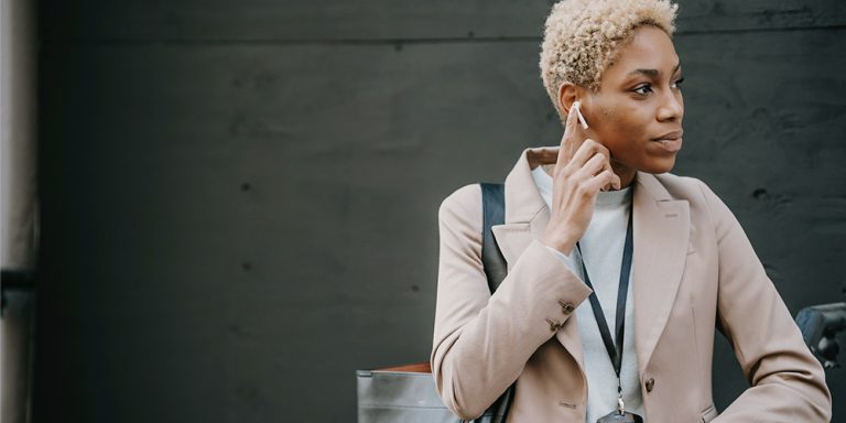 Business woman holding her hand to a headphone as she listens to important sound bites.