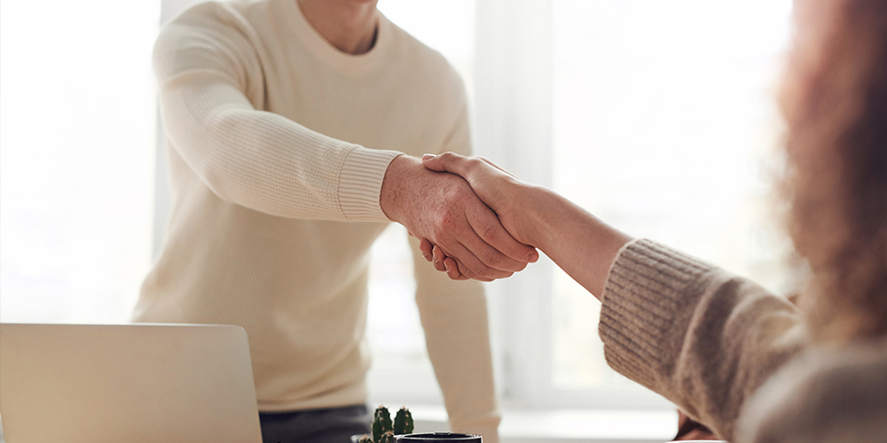 Two people shaking hands across the table, taking the opportunity to change jobs.