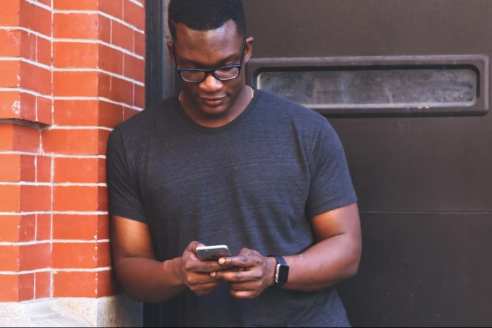 Man leaning against wall on phone representing marketing.