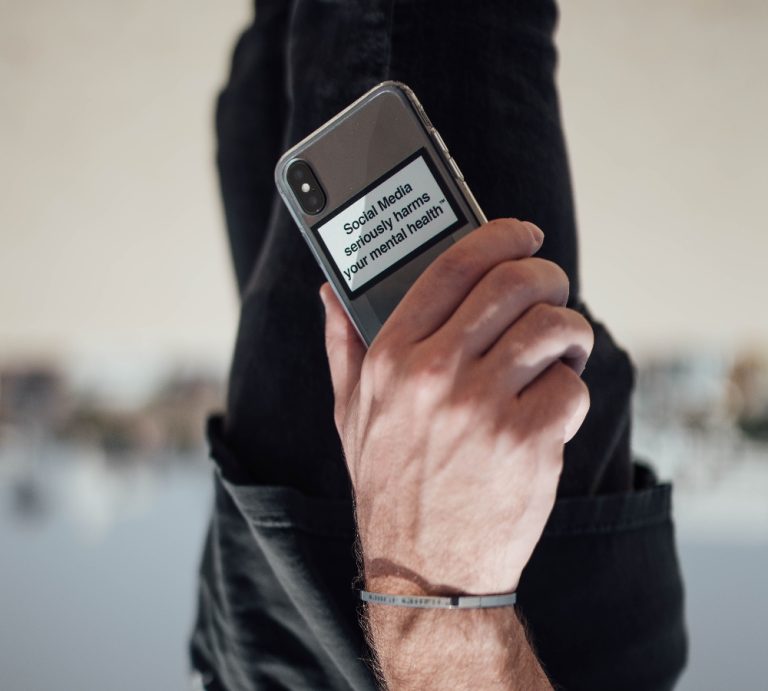 Upside down photo of man holding iphone case saying "social media seriously harms your mental health" representing dopamine.