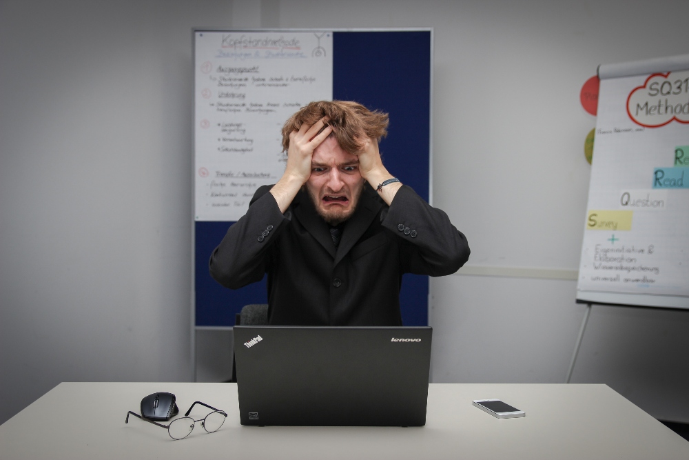 Man staring at computer in shock after interview decline.
