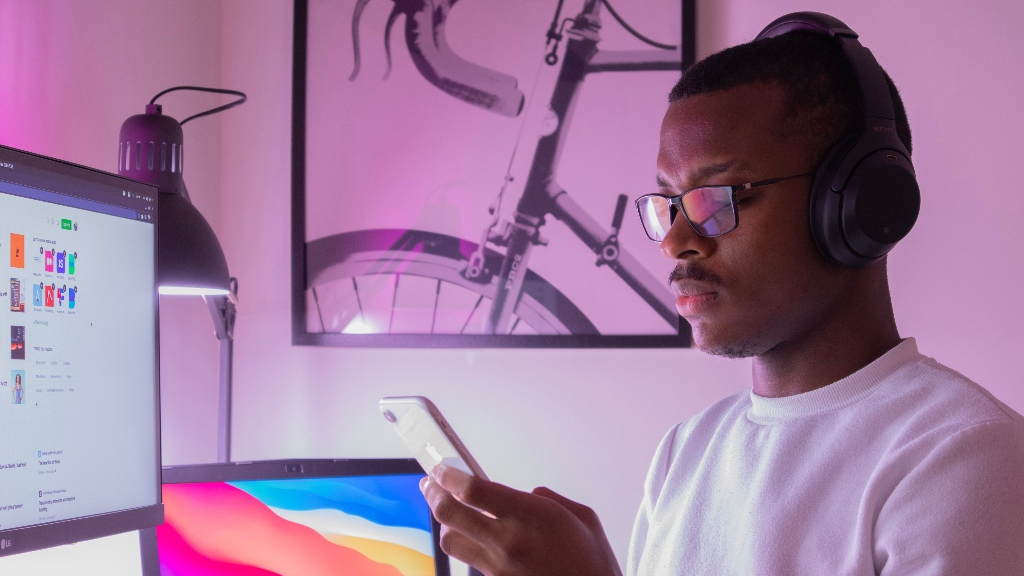 Person using computer, laptop, phone, and headphones representing a neurodivergent worker remote worker, Person using computer, laptop, phone, and headphones representing a neurodivergent worker