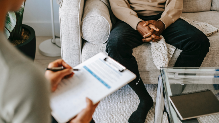 Cut off view of a client and consultant filling out paperwork while they determine companies involvement.